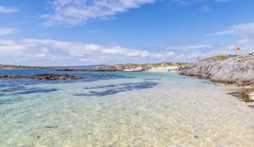 a sandy beach with clear water and rocks at Blue house, Carraroe in Carraroe