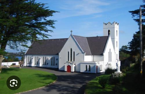 a white church with a black roof at Blue house, Carraroe in Carraroe