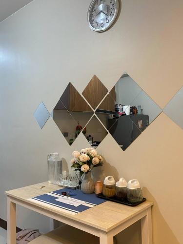 a table with a vase of flowers and a clock at Saekyung Condo in Lapu Lapu City