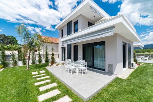 a white house with a table and chairs in the yard at Nefeli & Nefeli Luxury Residential Complexes in Ofrínion