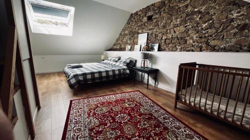 une chambre avec un lit et un mur en pierre dans l'établissement Ancienne école proche du Puy du Fou, à Montigné-sur-Moine
