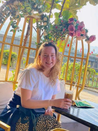 a woman sitting at a table with a drink at Sky Hotel & Homestay Ha Giang in Ha Giang