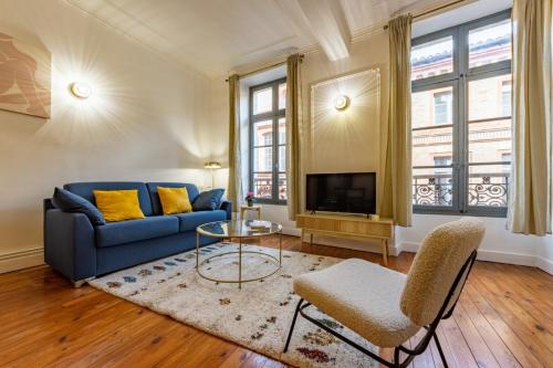 a living room with a blue couch and a tv at Le Contemporain - Charme et élégance in Montauban