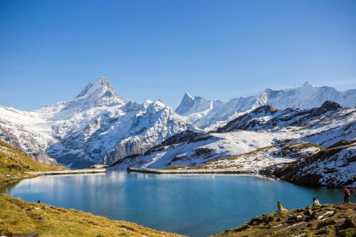 a mountain lake with snow covered mountains in the background at Guardian Gate Lodge in Iseltwald