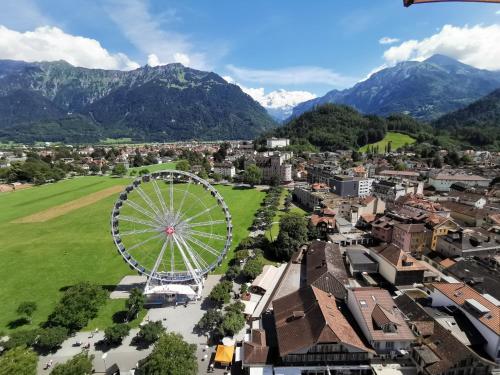 a ferris wheel in a city with mountains in the background at Guardian Gate Lodge in Iseltwald