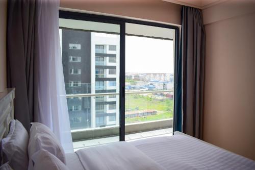 een slaapkamer met een bed en een groot raam bij Luxe Homes by cassie in Nairobi