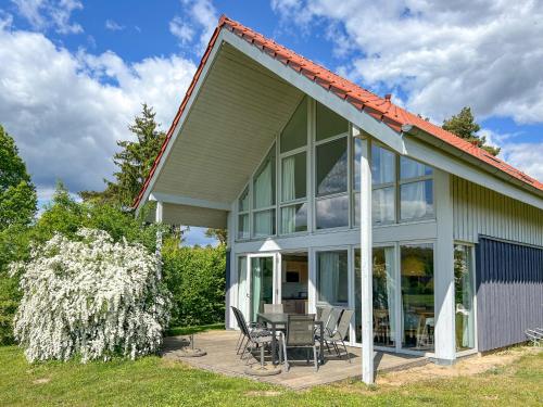 a house with a porch with chairs and a table at Ferienhaus Wiesengeflüster S1 - mit Sauna, Kamin und Workation an der Müritz in Marienfelde
