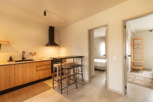 Una cocina con encimera, mesa y taburete. en Vila Laura, en Porto Covo