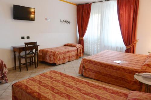 a hotel room with two beds and a table at Hotel Ristorante Italia in Certosa di Pavia