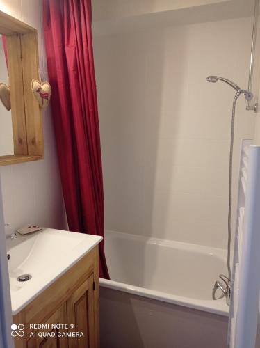 La salle de bains est pourvue d'une baignoire blanche et d'un rideau de douche rouge. dans l'établissement Appart à Puy Saint Vincent 1700 Rés Emeraude, à Puy-Saint-Vincent