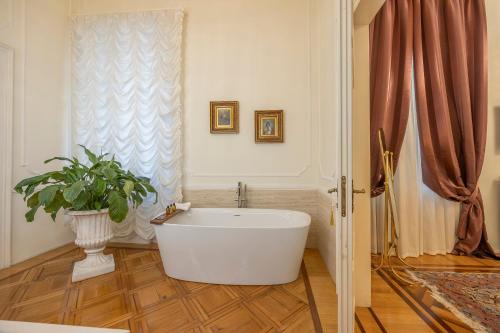 a bathroom with a white tub and a potted plant at Palazzo Monga Boutique Guesthouse in Verona
