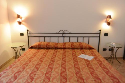 a bedroom with a bed with a comforter and two tables at Hotel Ristorante Italia in Certosa di Pavia