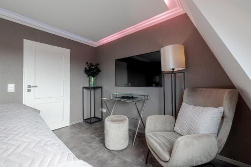 a bedroom with a bed and a chair and a tv at Strönhof Kampen in Kampen