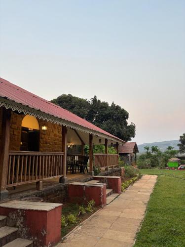 a house with a porch and a table on it at Madhuvan Retreat Resort Amba in Chandoli