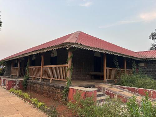 a house with a red roof and a porch at Madhuvan Retreat Resort Amba in Chandoli