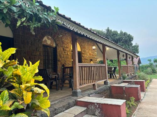 a house with a porch with tables and chairs at Madhuvan Retreat Resort Amba in Chandoli