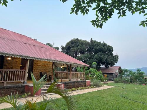 a house with a red roof and a yard at Madhuvan Retreat Resort Amba in Chandoli