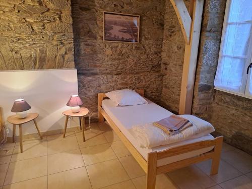 Cette petite chambre comprend un lit et deux tables. dans l'établissement Maison du barragiste, à Allineuc