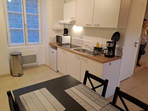 une cuisine avec des armoires blanches, une table et un micro-ondes dans l'établissement Maison du barragiste, à Allineuc