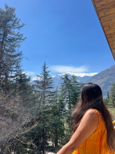 a woman looking out of a window at the mountains at The heavens place wooden room in Nagar