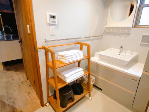 熊本市にあるSUMITSUGU HOUSE Atelierの洗面台とタオルの棚を備えたバスルーム