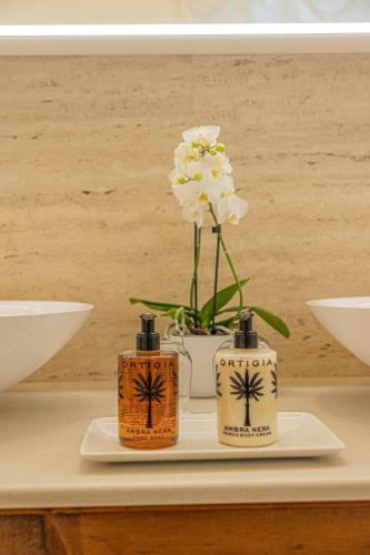 a table with two bottles and a vase with flowers at Palazzo Monga Boutique Guesthouse in Verona
