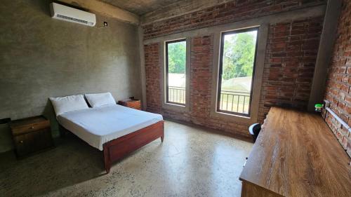 a bedroom with a bed and a brick wall at Sandalanaka Rustic Vila in Dankotuwa