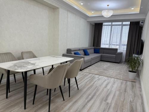 a living room with a table and chairs and a couch at Bay Tash Tower in Bishkek