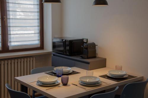 a kitchen with a table with plates and a microwave at Blue Apartment - Verona&Lake in Bussolengo