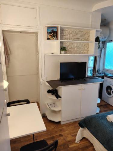 une petite pièce blanche avec une télévision sur un bureau dans l'établissement PARIS Vincennes authentique -`ღ, à Vincennes