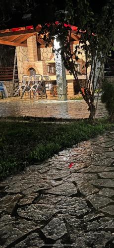 a stone walkway with chairs and a table and a tree at Το πετρινο σπιτι του Καστρη! Με θεα τα Μετεωρα in Kalabaka