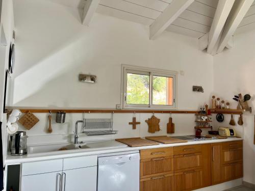 une cuisine blanche avec un évier et une fenêtre dans l'établissement Villa contemporaine au calme proche mer et golf, à Saint-Cyr-sur-Mer