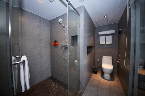 a bathroom with a toilet and a glass shower at Orange Hotel Shanghai Hongkou Football Stadium Branch in Shanghai