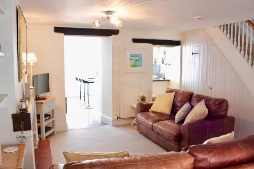 a living room with a brown couch and a staircase at Stylish, central Beaumaris cottage in Beaumaris