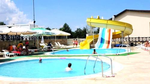a pool with a slide and people in the water at Mountainview Apartment Ski, Spa & Thermal in Bansko