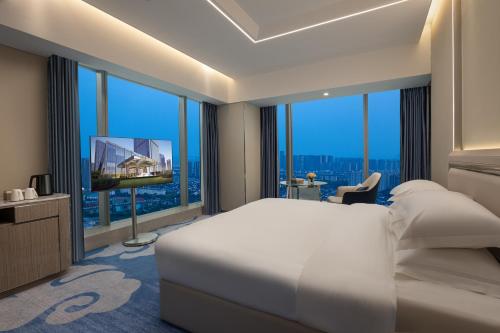 a hotel room with a bed and a large window at Wyndham Shaoxing Keqiao in Shaoxing