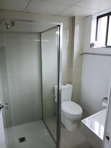 a bathroom with a toilet and a glass shower at Coastal Bay Motel in Coffs Harbour