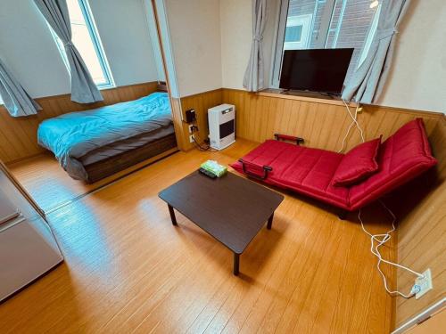 a living room with a red couch and a bed at Choyo 103 in Sapporo