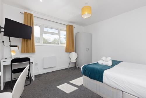 a bedroom with a bed and a desk and a television at South Harrow Apartment in London