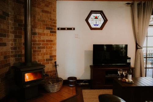 ein Wohnzimmer mit Kamin und Fernseher in der Unterkunft Clover Cottage Country Retreat in Manjimup