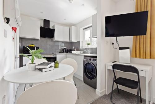 a small kitchen with a white table and chairs and a table at South Harrow Apartment in London
