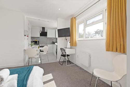 a white room with a bed and a kitchen at South Harrow Apartment in London