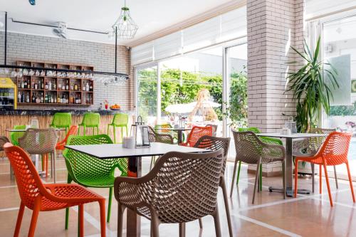 a restaurant with colorful chairs and tables and windows at Kleopatra Tuna Apart Hotel in Alanya