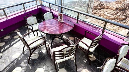 a purple table and chairs on a balcony with a view at Oryx Grand Hotel Jebel Hafeet in Al Ain