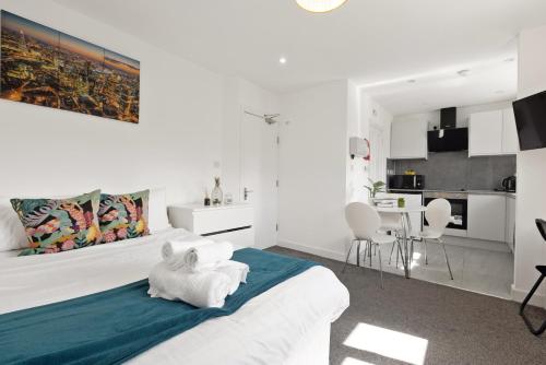 a white bedroom with a large bed and a kitchen at South Harrow Apartment in London