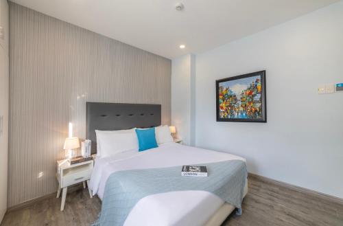 a bedroom with a large white bed and a night stand at Hese Boutique Hotel & Apartment in Vung Tau