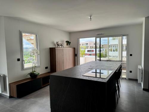 a kitchen with a black island in a room with windows at Skyline Rooftop Swim Spa in Montpellier