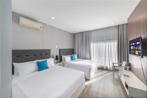 a hotel room with two beds and a television at Hese Boutique Hotel & Apartment in Vung Tau