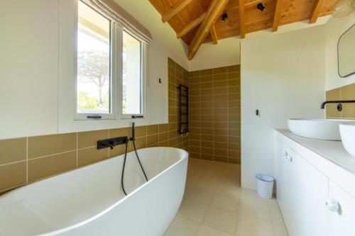 une salle de bain avec une baignoire et un lavabo dans l'établissement Attraktive Familien-Villa im Herzen von Cap Ferret, à Cap-Ferret