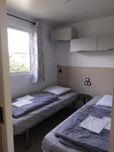 deux lits dans une petite pièce avec une fenêtre dans l'établissement Mobile home camping 5 étoiles, à Torreilles